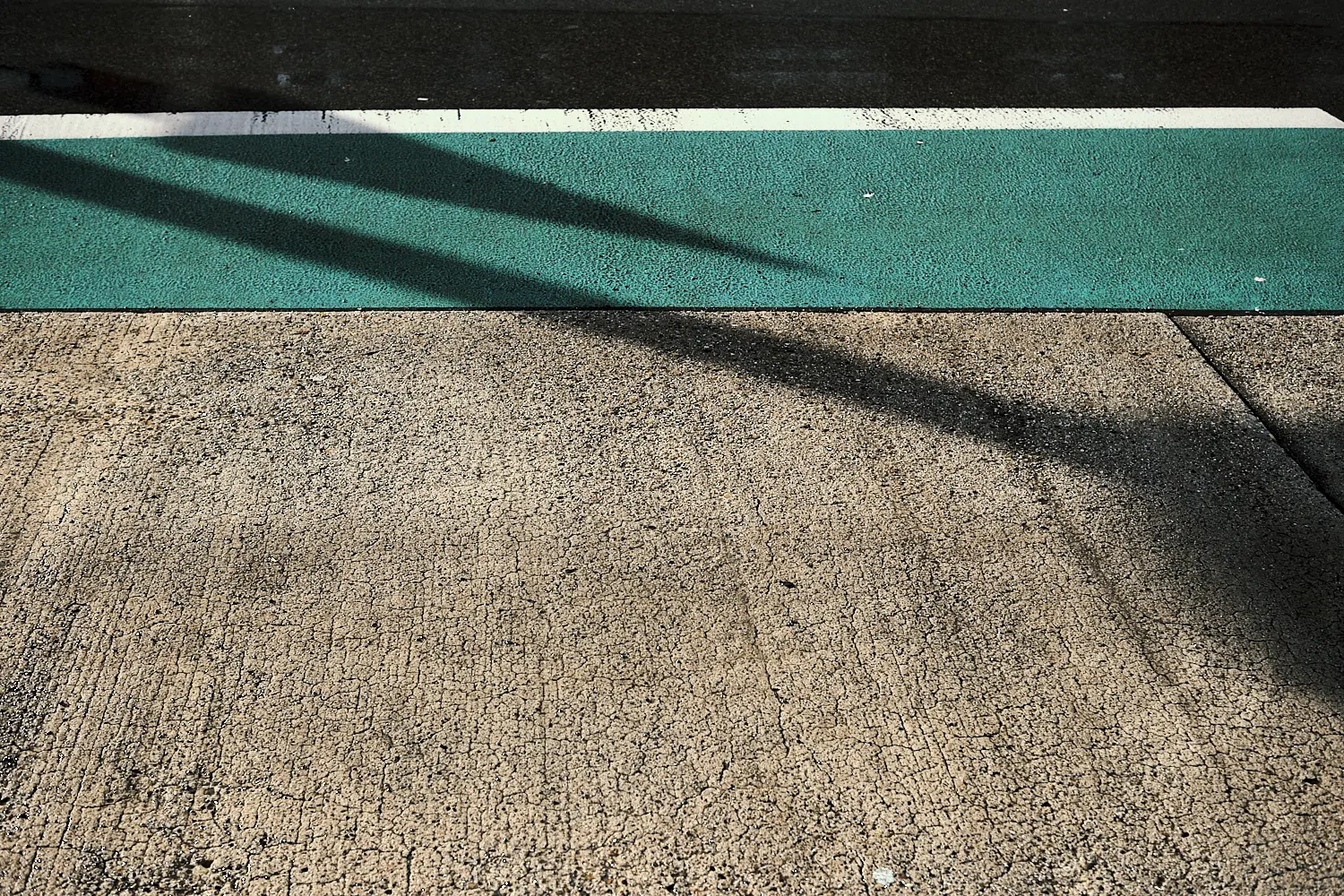 schatten der Verkehrsschilder auf dem grünen Radstreifen