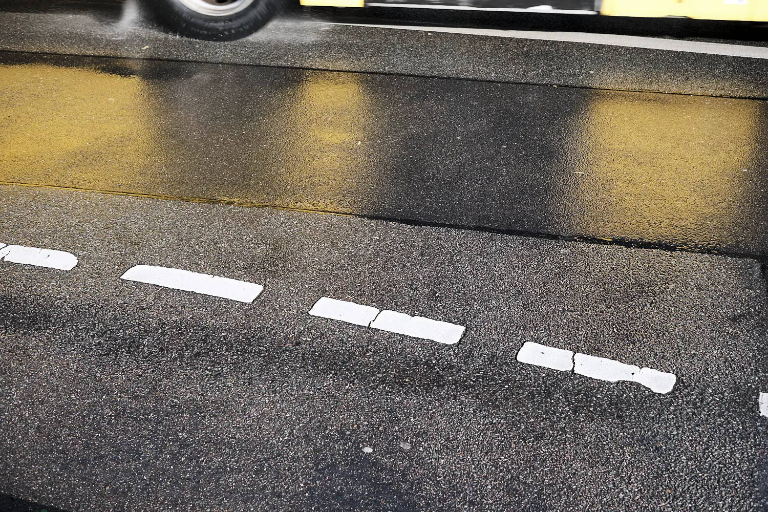 Bus spiegelt sich auf der regennassen Fahrbahn