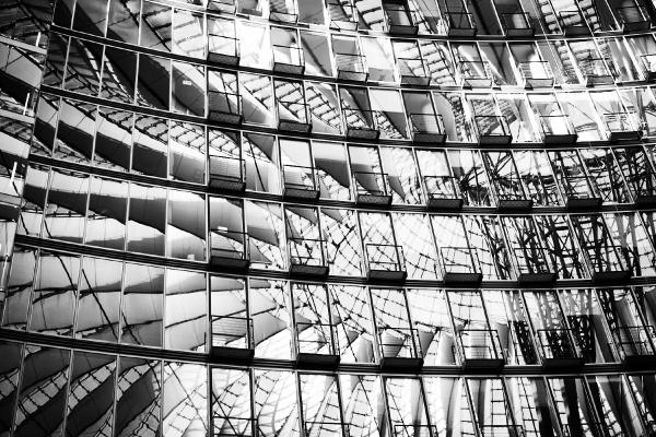 Schwarzweiß-Aufnahme der gespiegelten Glasfassade des Sony Centers in Berlin mit geometrischen Mustern.