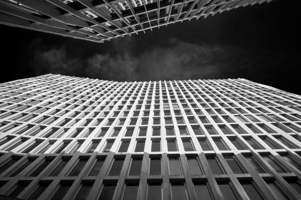 Low-angle view of a modern glass and steel office building facade with repetitive window pattern against dark sky in Berlin